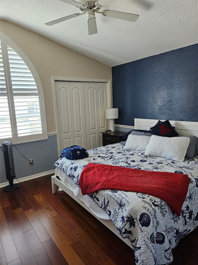 bedroom featuring ceiling fan, dark hardwood / wood-style floors, a textured ceiling, vaulted ceiling, and a closet