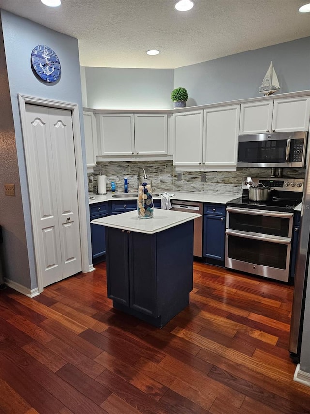 kitchen with blue cabinets, appliances with stainless steel finishes, sink, and white cabinets