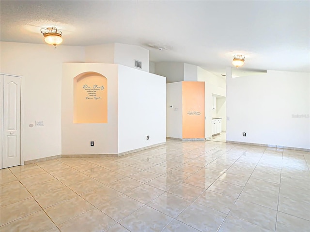 tiled empty room with lofted ceiling