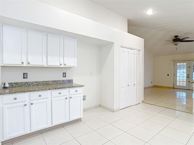 kitchen with white cabinetry, light tile patterned floors, and dark stone countertops