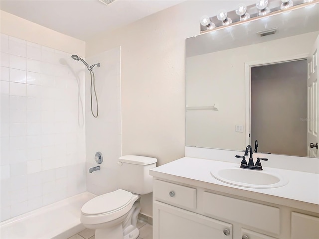 bathroom featuring vanity, tile patterned flooring, toilet, and a tile shower