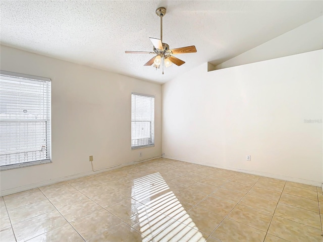 empty room with vaulted ceiling, light tile patterned flooring, ceiling fan, and a textured ceiling