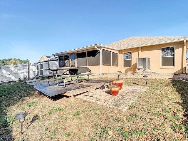 back of house with a sunroom, a deck, and a lawn