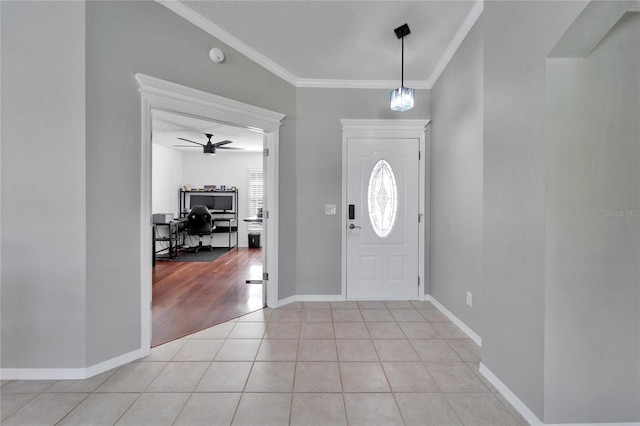 foyer entrance with crown molding, ceiling fan, and light tile patterned flooring