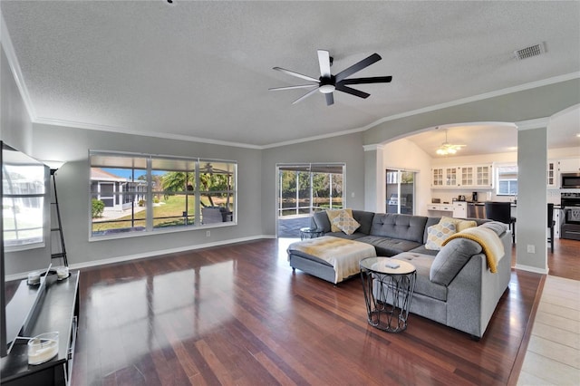 living room with crown molding, ceiling fan, a textured ceiling, dark hardwood / wood-style flooring, and vaulted ceiling