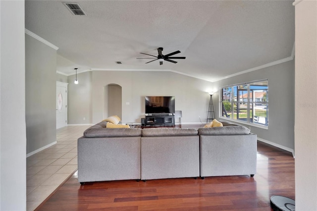 living room with hardwood / wood-style flooring, vaulted ceiling, ornamental molding, and ceiling fan