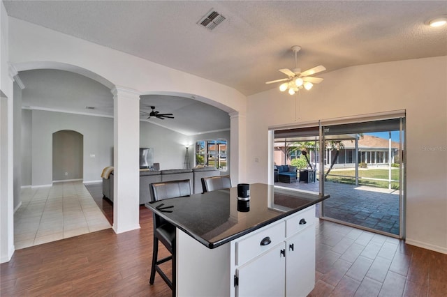 kitchen with white cabinetry, lofted ceiling, a kitchen island, and a breakfast bar area