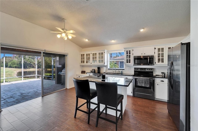 kitchen featuring a kitchen island, white cabinetry, lofted ceiling, sink, and stainless steel appliances