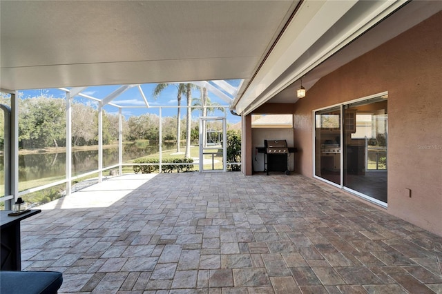 view of patio / terrace with exterior kitchen, a water view, area for grilling, and glass enclosure