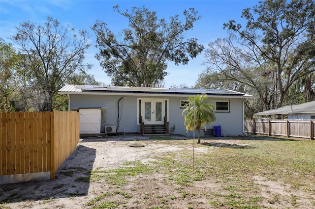 rear view of house featuring a garage, a lawn, french doors, and solar panels