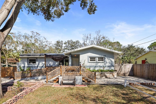 back of house featuring roof mounted solar panels, a fenced backyard, a yard, and stucco siding