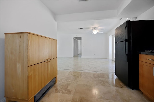 kitchen featuring ceiling fan, light tile patterned floors, baseboards, freestanding refrigerator, and dark countertops