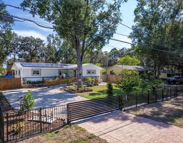 view of front facade featuring decorative driveway, a fenced front yard, a front yard, and a gate