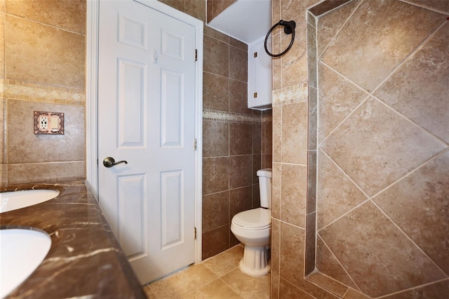 full bathroom featuring double vanity, tile patterned flooring, toilet, and tile walls