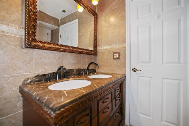 full bathroom with visible vents, a sink, and tile walls