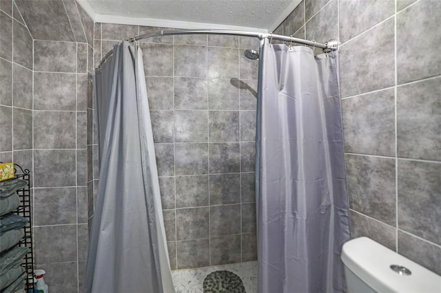 bathroom with a textured ceiling, a tile shower, and toilet