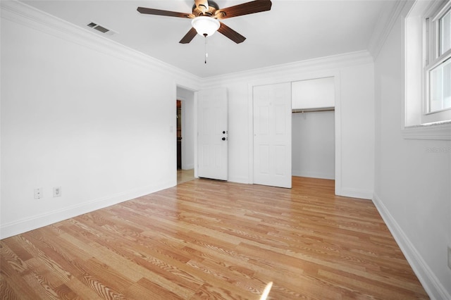 unfurnished bedroom featuring baseboards, visible vents, ornamental molding, light wood-style floors, and a closet