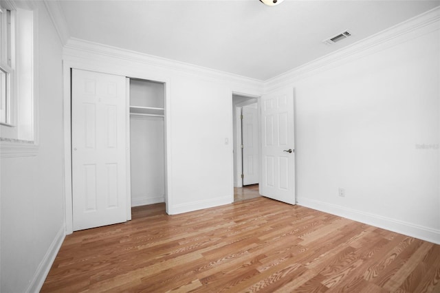 unfurnished bedroom with visible vents, baseboards, light wood-style floors, a closet, and crown molding