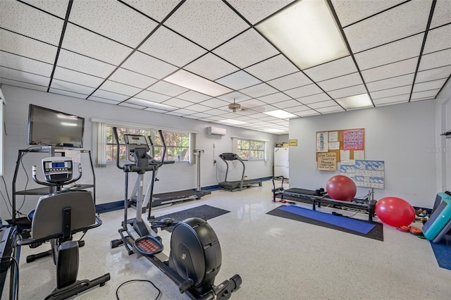 exercise room featuring a paneled ceiling and a wall unit AC