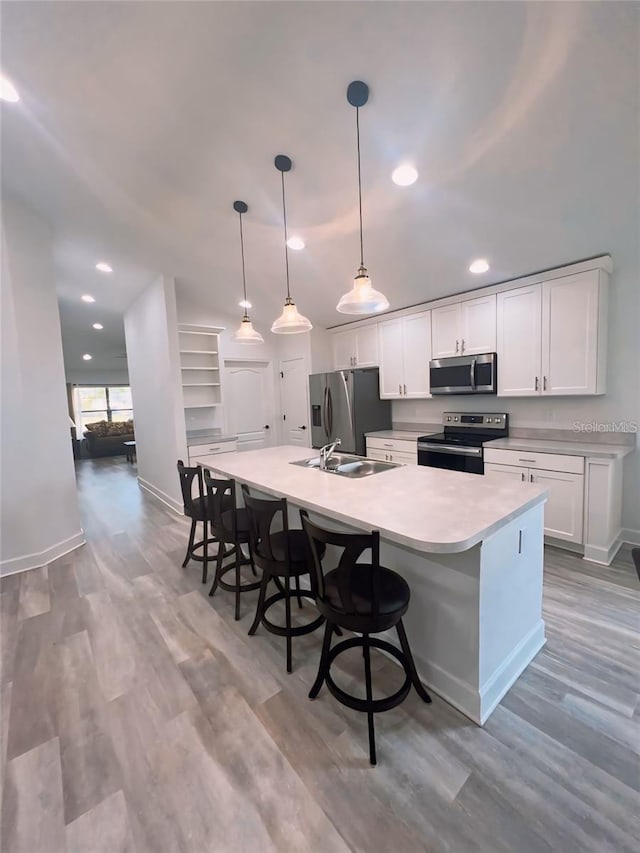 kitchen featuring pendant lighting, sink, appliances with stainless steel finishes, a spacious island, and white cabinets