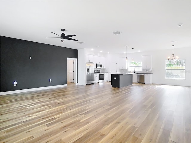 unfurnished living room with sink, ceiling fan with notable chandelier, and light hardwood / wood-style flooring