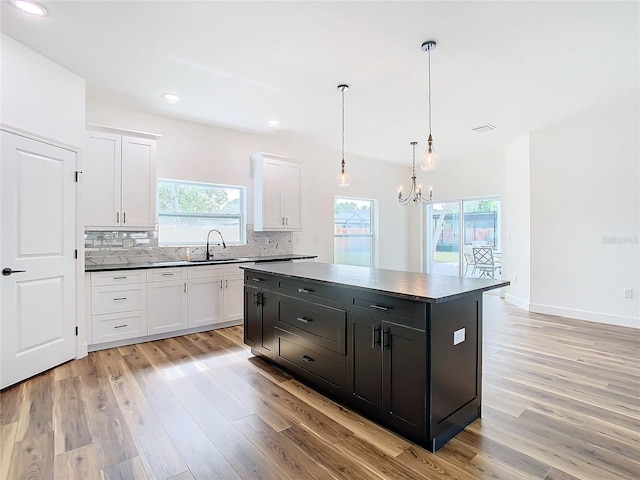 kitchen featuring white cabinetry, a center island, decorative backsplash, and pendant lighting