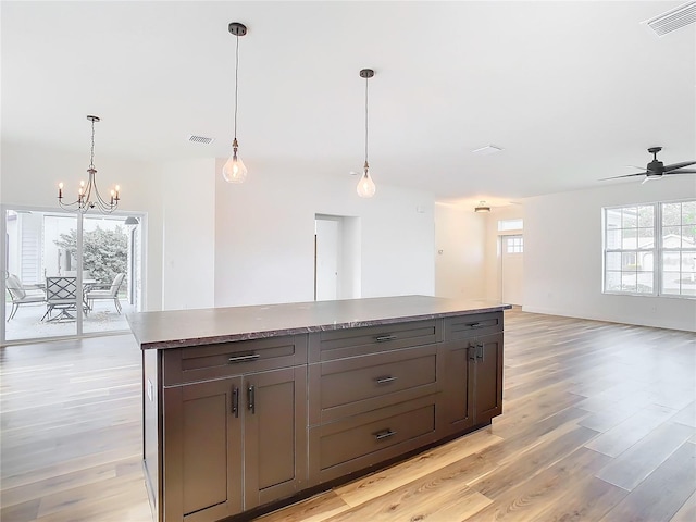 kitchen with a wealth of natural light, a kitchen island, pendant lighting, and light hardwood / wood-style floors