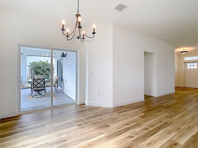 unfurnished dining area featuring a notable chandelier and light wood-type flooring