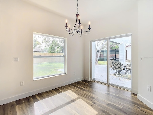 unfurnished dining area featuring a notable chandelier, wood-type flooring, and a wealth of natural light