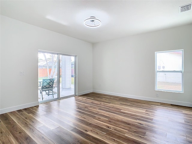 spare room featuring a wealth of natural light and dark hardwood / wood-style floors