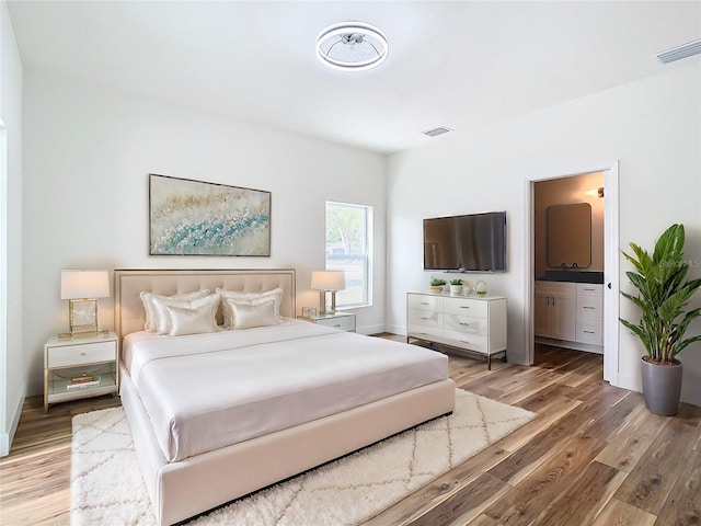 bedroom featuring ensuite bath and light wood-type flooring