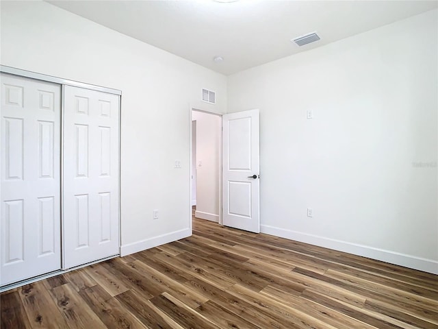 unfurnished bedroom with dark hardwood / wood-style floors and a closet