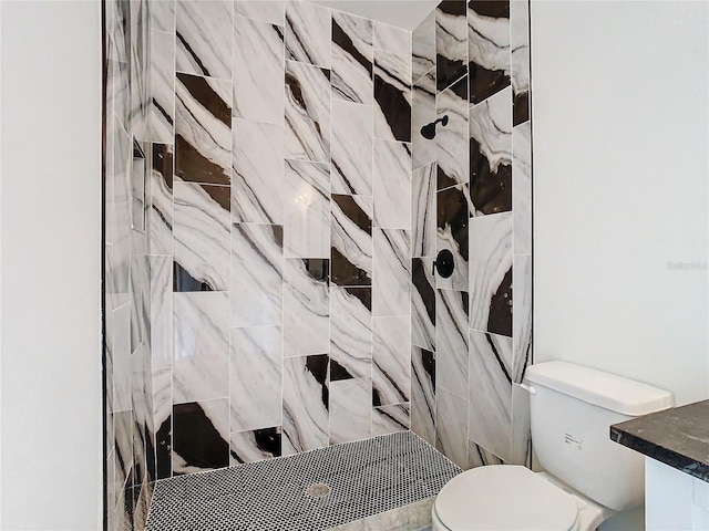 bathroom featuring a tile shower and toilet