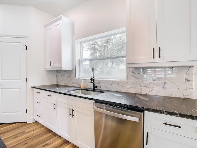 kitchen featuring white cabinetry, stainless steel dishwasher, sink, and dark stone countertops