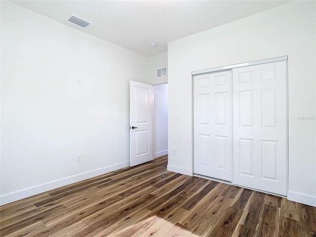 unfurnished bedroom with dark hardwood / wood-style floors and a closet