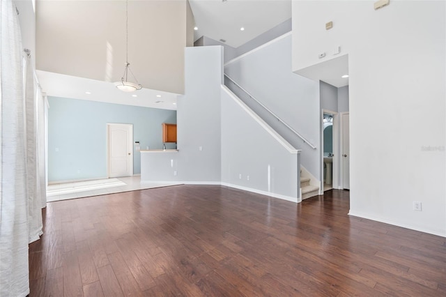 unfurnished living room with a towering ceiling and dark hardwood / wood-style flooring