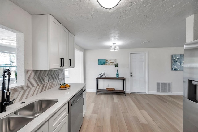 kitchen with white cabinetry, sink, light hardwood / wood-style flooring, and stainless steel dishwasher