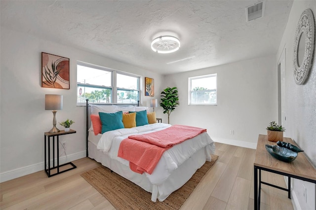 bedroom with a textured ceiling and light hardwood / wood-style flooring