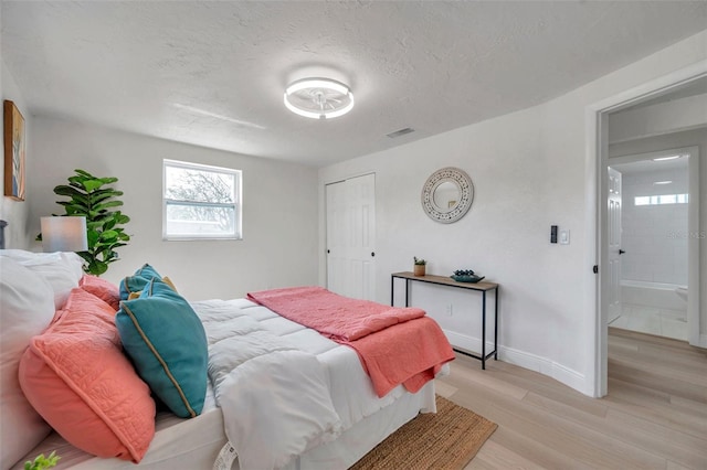 bedroom featuring a closet, light hardwood / wood-style flooring, and a textured ceiling