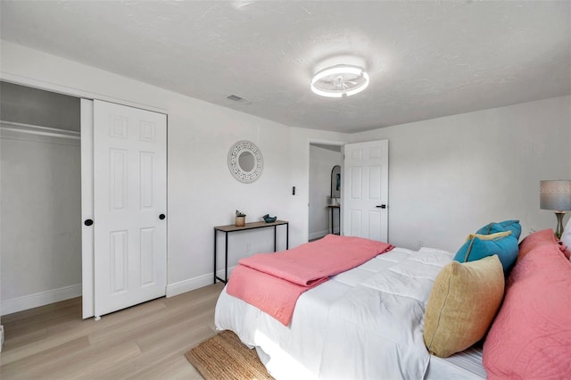 bedroom with a closet, a textured ceiling, and light wood-type flooring