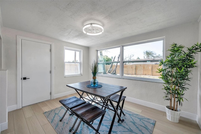 dining space with a textured ceiling and light wood-type flooring