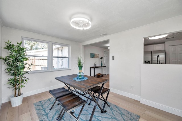 dining space featuring a textured ceiling and light wood-type flooring