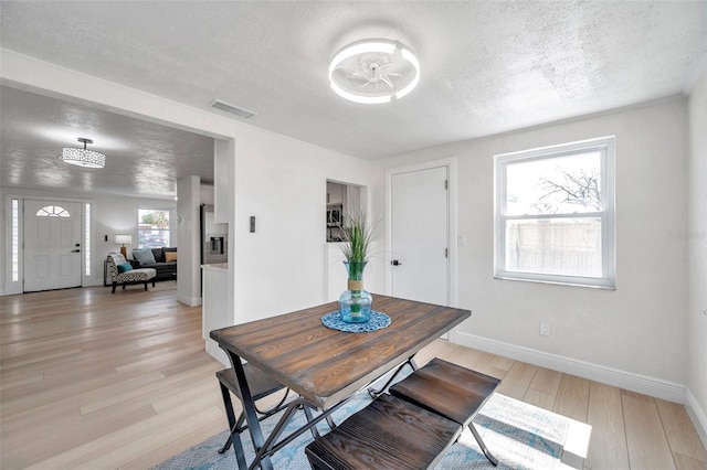 dining space with light hardwood / wood-style flooring and a textured ceiling