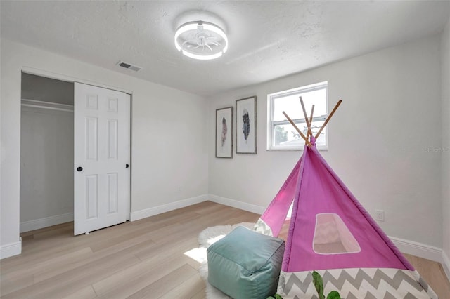 rec room featuring a textured ceiling and light hardwood / wood-style flooring