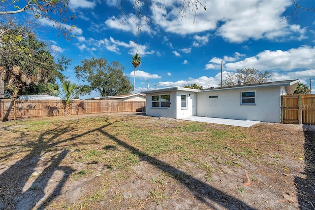 back of property with a yard and a patio