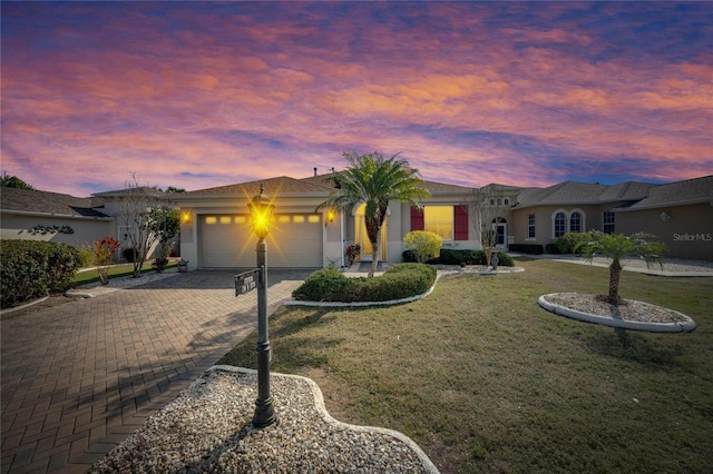 ranch-style home featuring a garage and a lawn