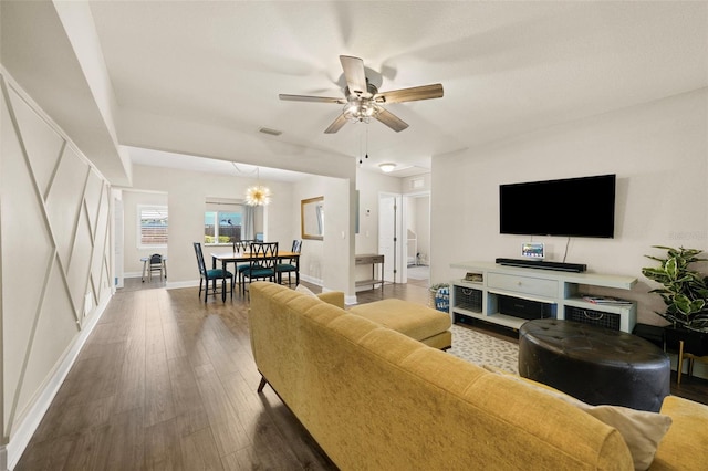 living room featuring ceiling fan with notable chandelier, hardwood / wood-style flooring, visible vents, and baseboards