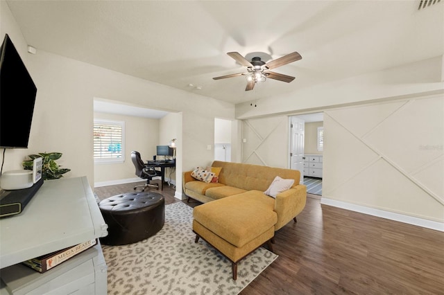 living area with a barn door, baseboards, visible vents, ceiling fan, and wood finished floors