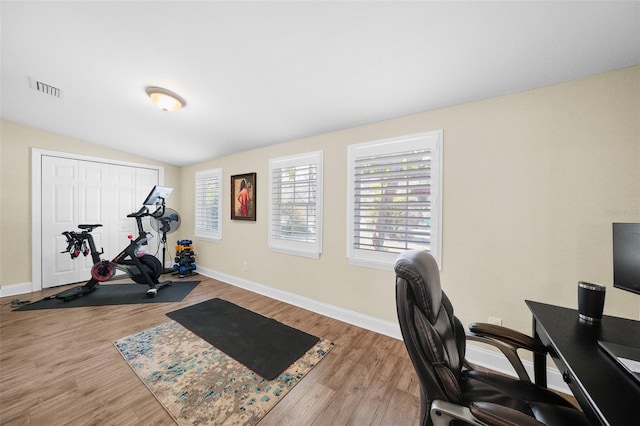 office featuring lofted ceiling, wood finished floors, visible vents, and baseboards