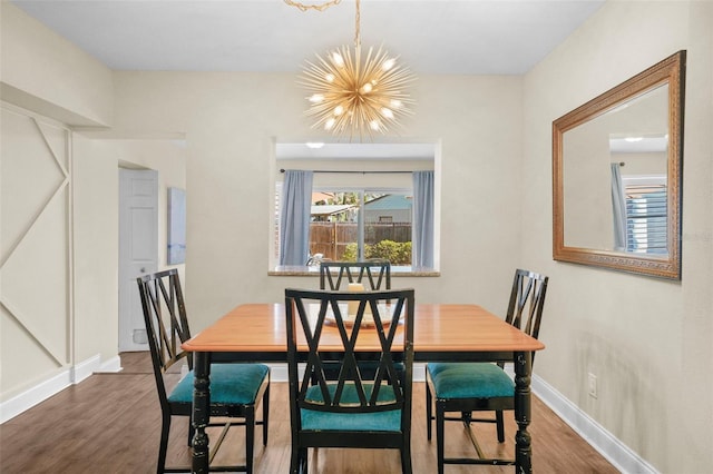 dining space with wood finished floors, baseboards, and an inviting chandelier